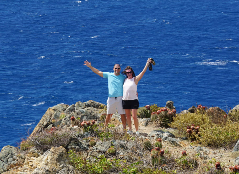 Two smiling people standing infront of the ocean